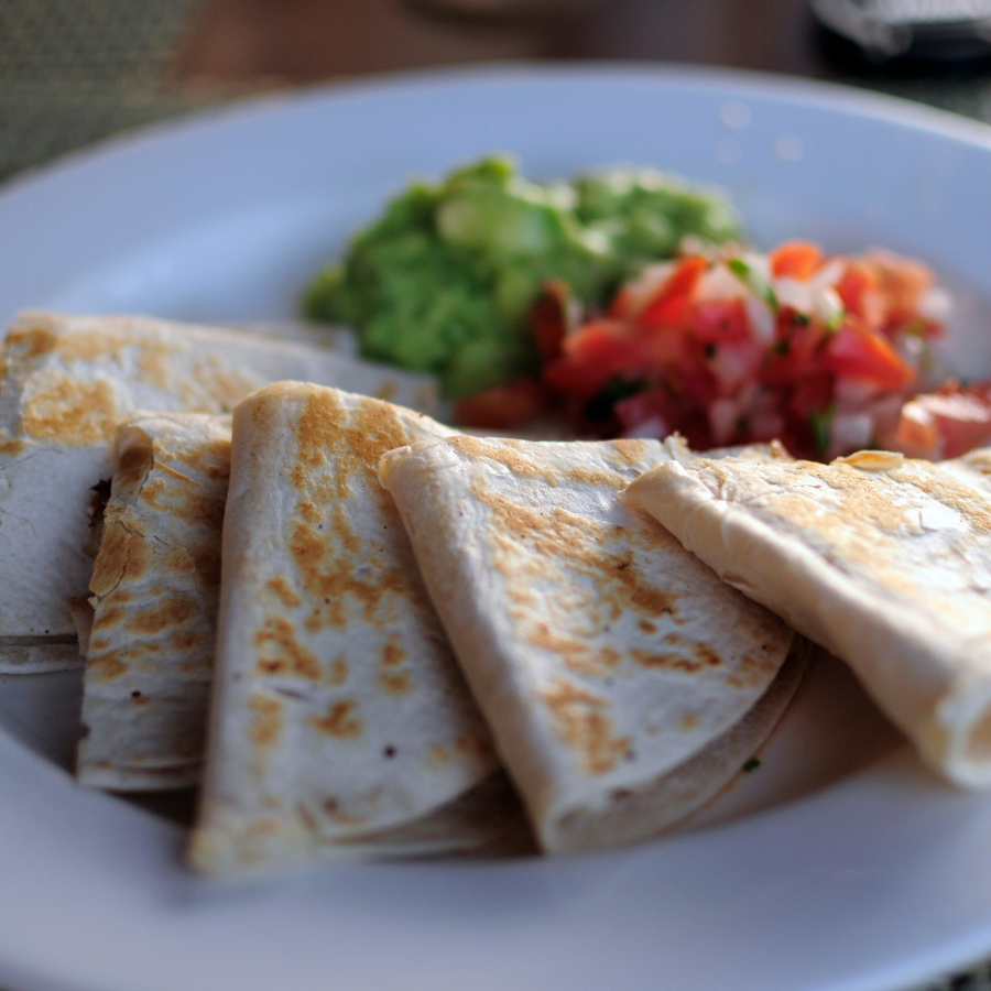 A quesadilla with salsa and guacamole.